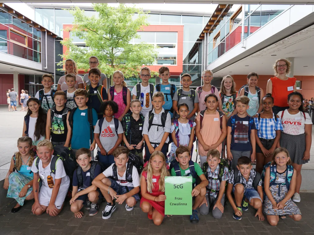 Klassenfoto einer neuen fünften Klasse mit grünem Schild.